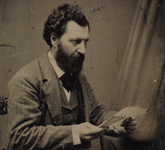 A black-and-white photograph of Louis Riel seated at a desk, ca. 1875