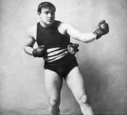 Black-and-white photograph a man wearing boxing gloves.