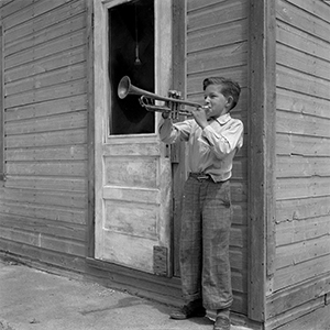 Black and white photograph of a young boy playing the trumpet.