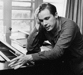 Black and white photograph of Glenn Gould leaning on a piano with his right hand holding his head.