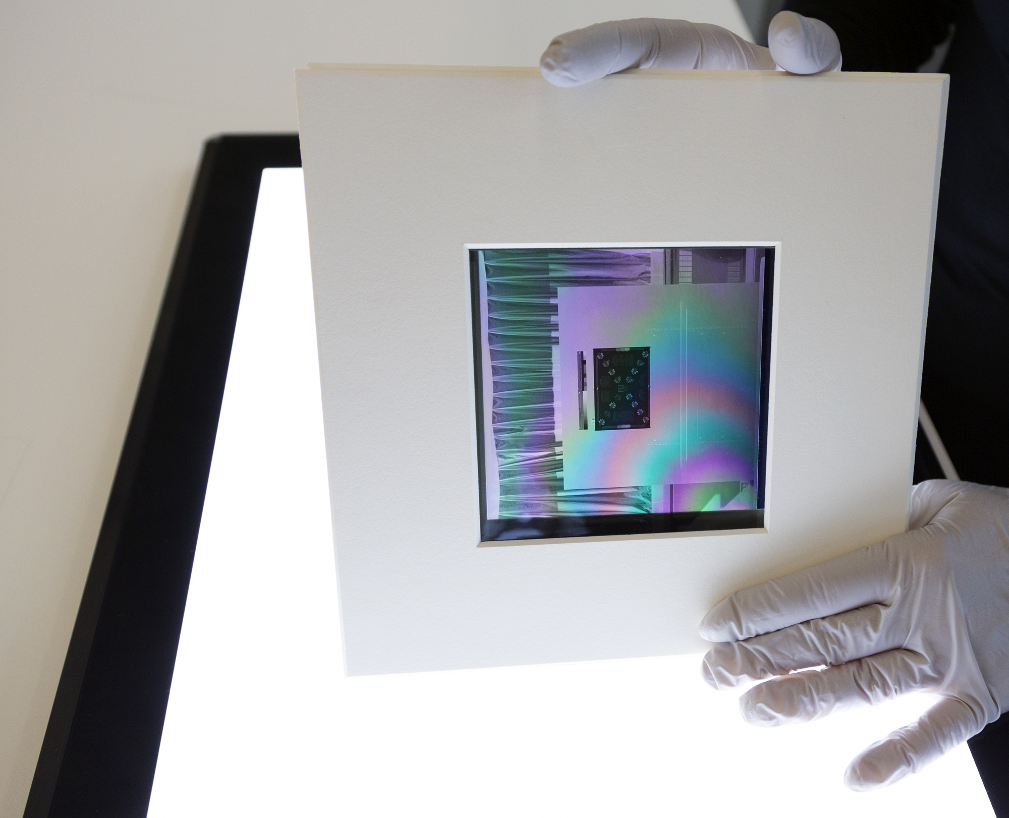 A negative between two polarizing filters showing a pink, blue, green rainbow effect on a light table.