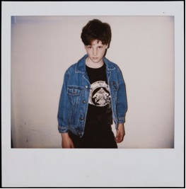 Boy in a jean jacket and a black t-shirt with writing.