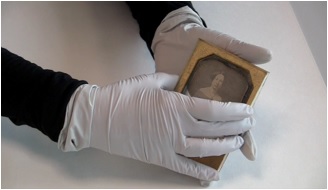 Close-up of someone removing the cover glass of a daguerreotype.