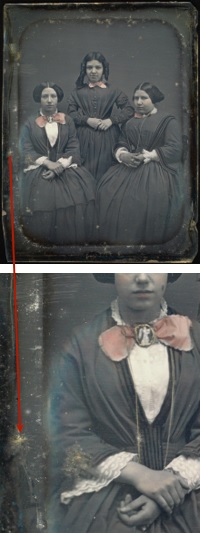 Three young girls; two are seated on either side, while one stands between. Mould is exhibited around the edges. A close-up of mould along the edge.