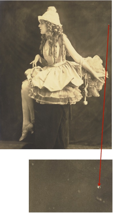 Profile of a young girl sitting on a stool with a fluffy skirt. This photograph exhibits a small puncture along the top right edge. A close-up of a small puncture.