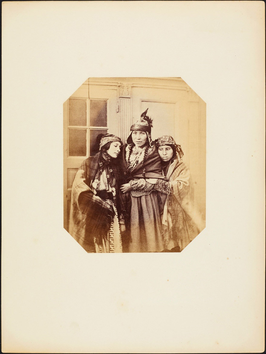 Three young girls huddled together, in front of a building.