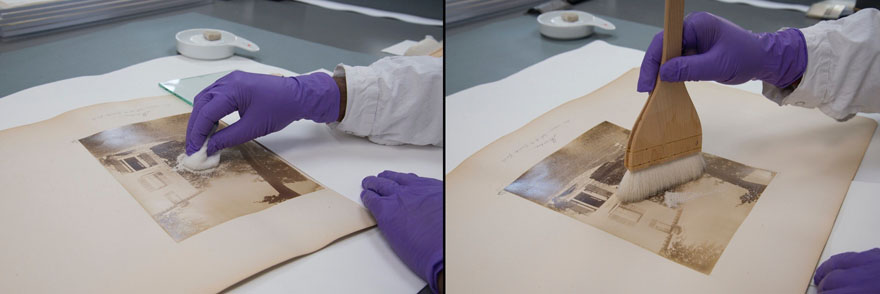 An image of a gloved hand rubbing small pieces of eraser with a cloth onto the surface of a photograph. Beside another image of a gloved hand brushing small pieces of eraser off the surface of the photograph.