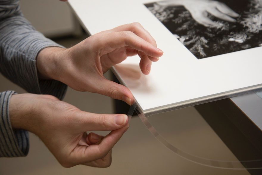 A person is applying tape to the edge of a matted photograph.