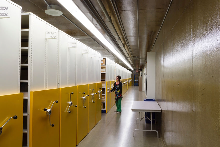 A long vault with movable storage racks. A woman moving one of the shelves.