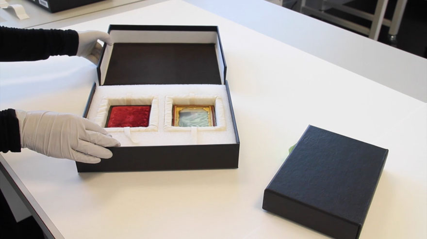 Two custom made Solander storage boxes on a table. One is opened, displaying a cased object inside.