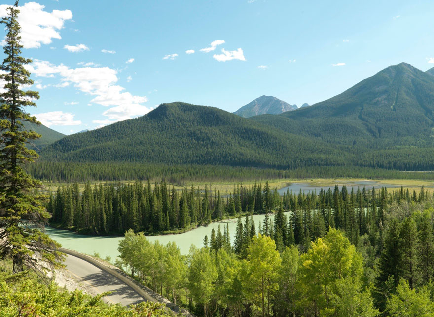 A colour positive photograph of a landscape with mountains in the background and a river in the foreground.