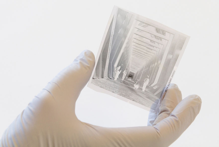 Hands with gloves holding the edges of a negative.