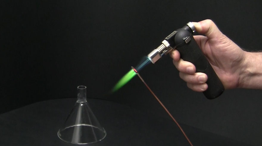 A copper wire is heated up with a torch. A blue flame is generated.