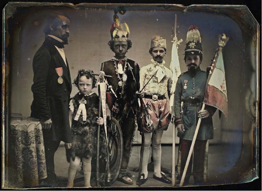 Credits: Image of a hand coloured photograph of a man and four boys dressed in costume.